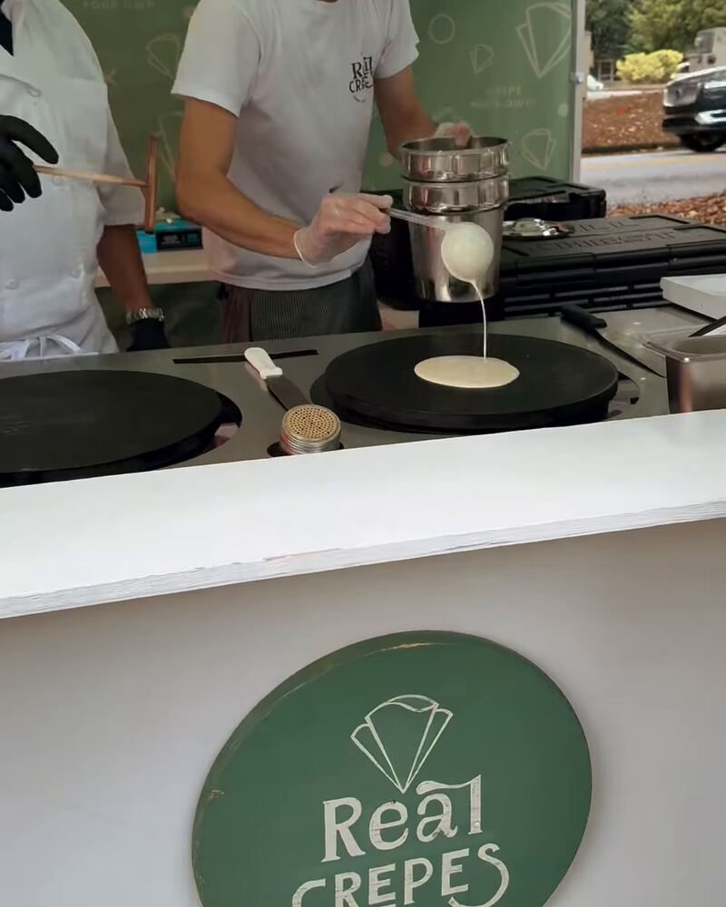 Fresh batter being poured onto a hot crepe griddle at a Real Crepes pop-up.
