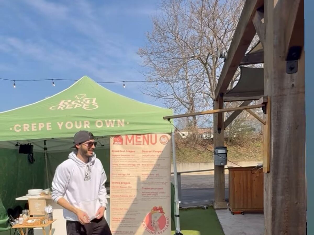 The green Real Crepes canopy and menu board set up for a pop-up.